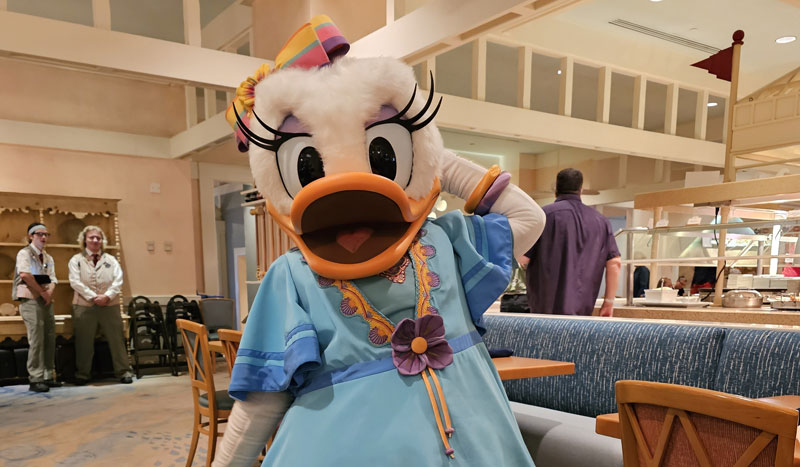 Daisy Duck in a pastel outfit greets guests at Chef Mickey's