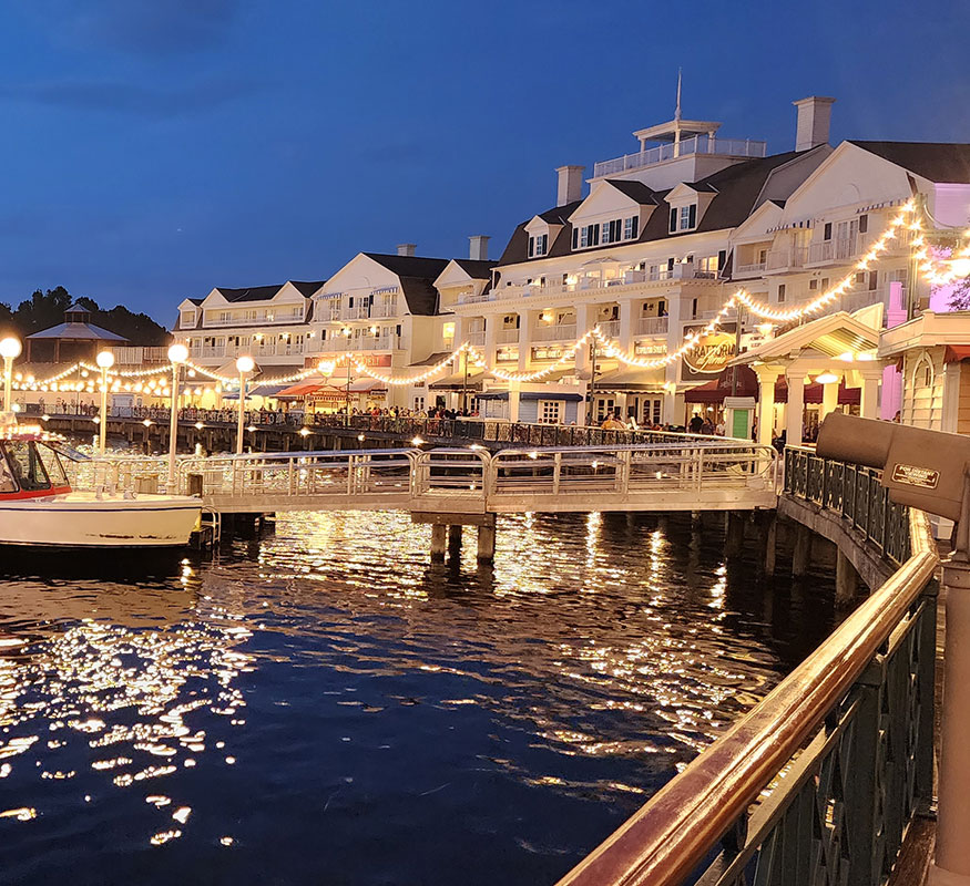 Disney's BoardWalk waterfront glows with strings of lights reflected in Crescent Lake