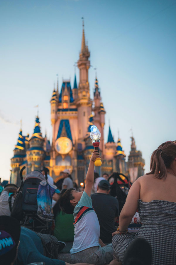 Cinderella Castle glows with evening lights as guests gather in the foreground