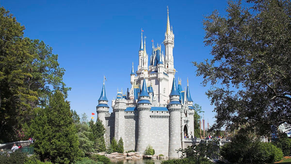 Cinderella Castle's tall spires rise between leafy trees at Magic Kingdom