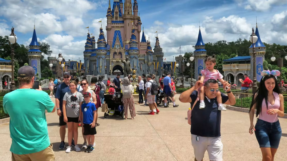 Guests walk toward Cinderella Castle across a busy Magic Kingdom plaza