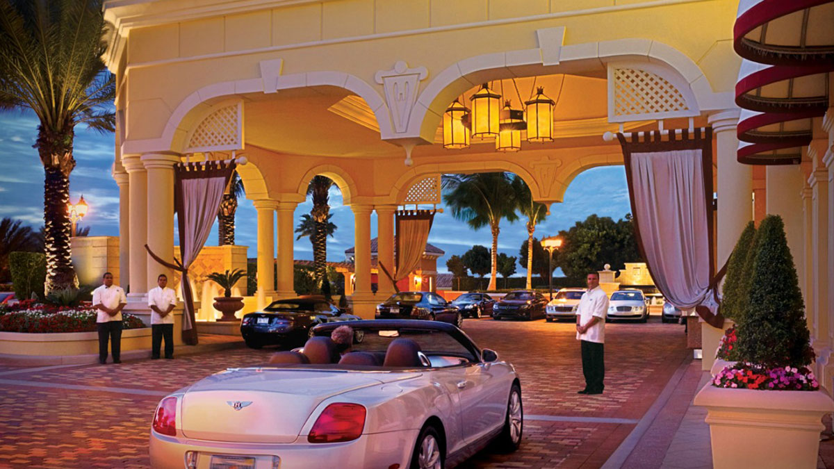 A luxury hotel lobby has curved purple seating, patterned carpet, and ornate golden lighting