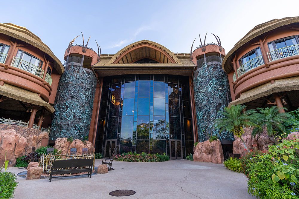 Kidani Village's entrance has tall glass doors, stone columns, and curved wooden rooflines